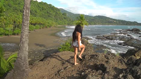 woman walking and climbing over rocks on coast of costa rica, south america