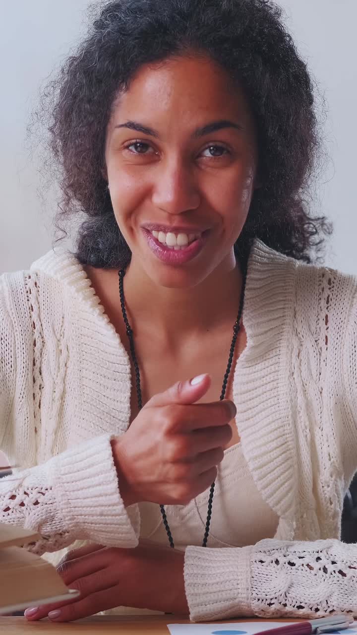 Giovane tutor afroamericana che parla e gesticola attivamente, ripresa dalla telecamera.