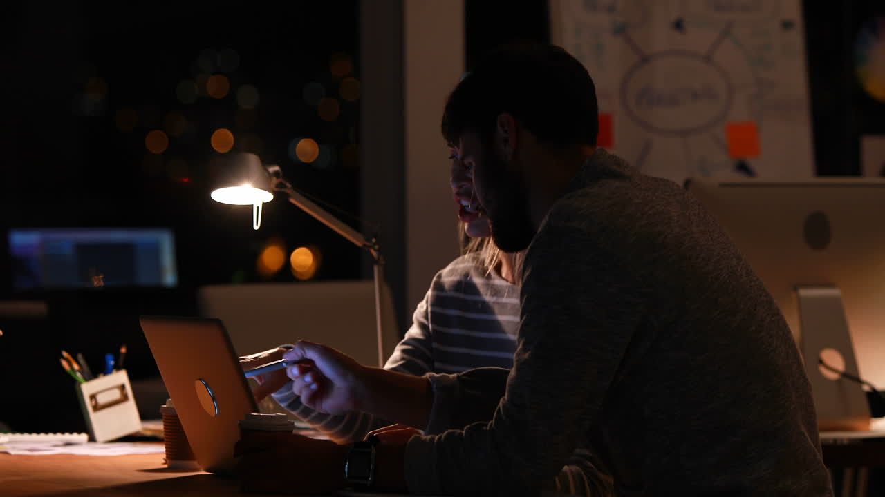 Casual colleagues working with computer at night