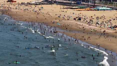 People-on-beach-and-shallows-on-hot-summer-day,-Scheveningen,-The-Hague