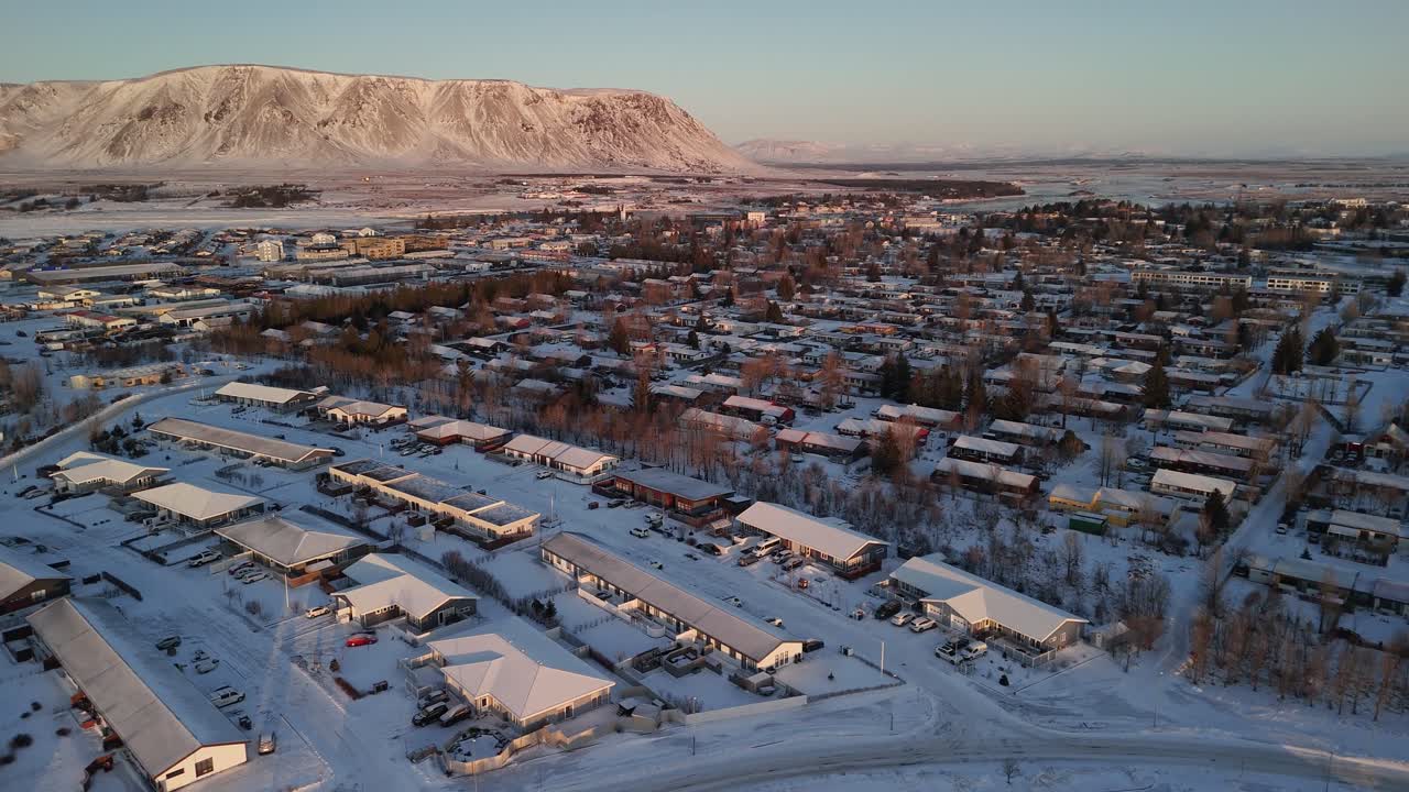 vecindario islandés nevado al amanecer. paisaje de invierno de nieve y montaña en la distancia. tiro aéreo de arriba hacia abajo. área de vivienda nevada en selfoss, islandia.