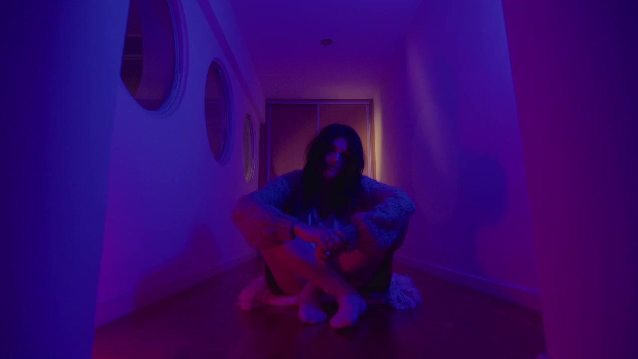 Donna depressa in posa in corridoio con luci al neon colorate