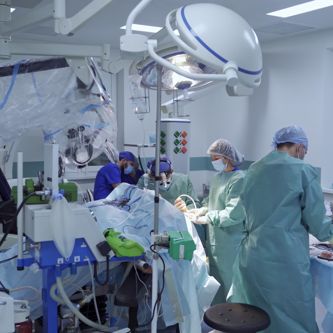 Teamwork of professional doctors in blue medical uniform conduct a neurosurgery. Neurosurgeons with a microscope