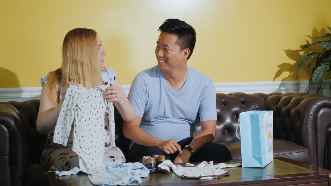 사랑하는 부부는 미래의 아기를 위해 옷을 본다