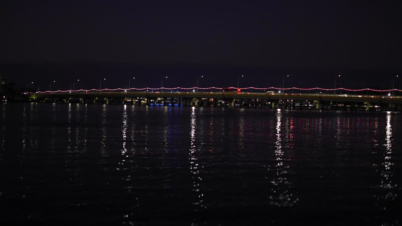 светильники моста отражаются на воде ночью.