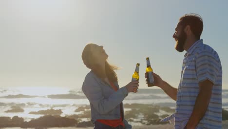 una joven pareja feliz tomando cerveza en la playa 4k