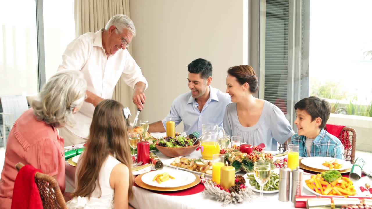 abuelo tallando pollo en la mesa de la cena para su familia