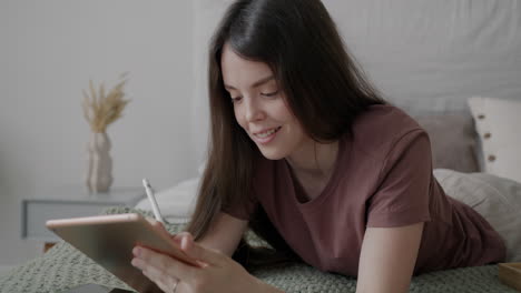 woman drawing on a tablet on a bed