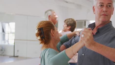 Caucasian-senior-couples-spending-time-together-in-a-ballroom-taking-part-in-dancing-class