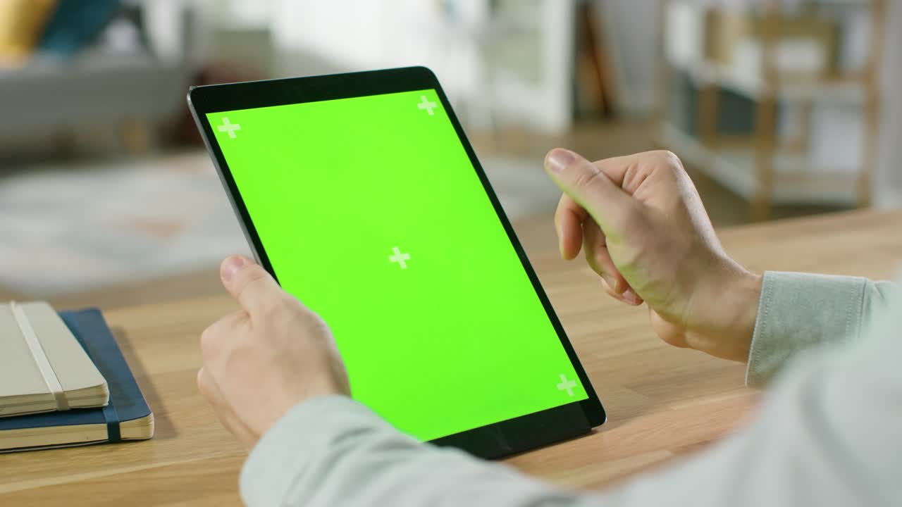 초록색 모형 화면에서 손의 제스처를 사용하는 남자, 그의 책상에 앉아있는 동안 포트레이트 모드에서 디지털 태블릿 컴퓨터.