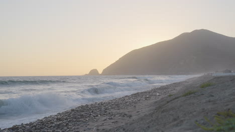 plan fixe au ralenti de vagues se brisant sur le rivage rocheux de la plage de mondo au coucher du soleil