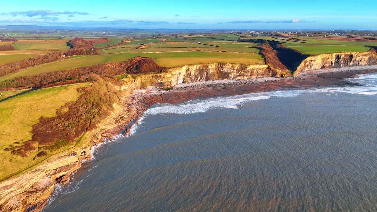 Prospettiva aerea di terreni agricoli verdi che incontrano scogliere marine scoscese. Vista dall'alto di campi agricoli e della costa rocciosa della Vale of Glamorgan a Southerndown.