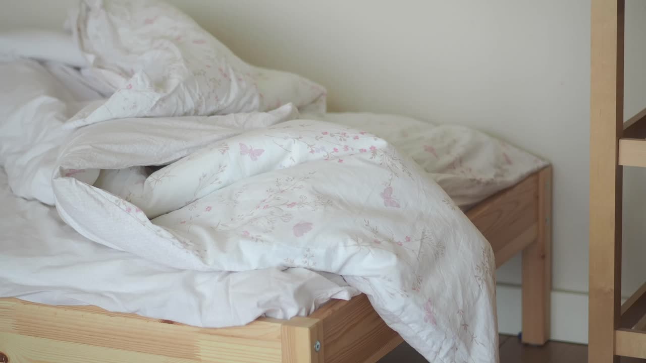 An unmade bed with white floral bedding