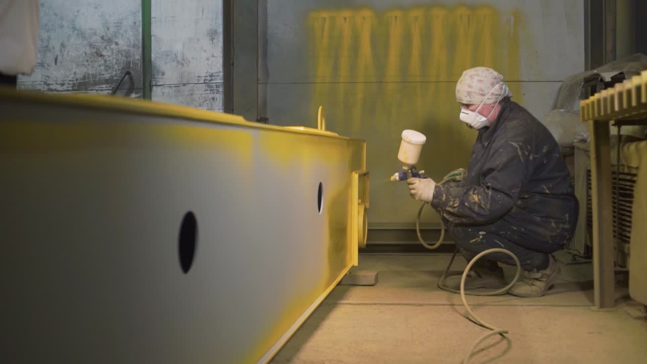 Obrero industrial pintando una viga metálica.