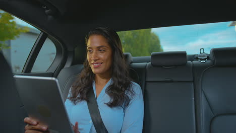 Mujer-De-Negocios-Madura-Sentada-En-El-Asiento-Trasero-De-Un-Taxi-O-Coche-Trabajando-En-Una-Tableta-Digital