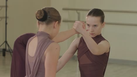 un grupo de jóvenes estudiantes de ballet con ropa de baile negra practicando posiciones en un amplio estudio de ballet con pisos de madera y barras montadas en la pared. expresiones enfocadas y movimientos sincronizados.