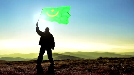 hombre ganador de silueta exitosa agitando la bandera de mauritania en la cima de la montaña, fondo de bucle de cinemagraph