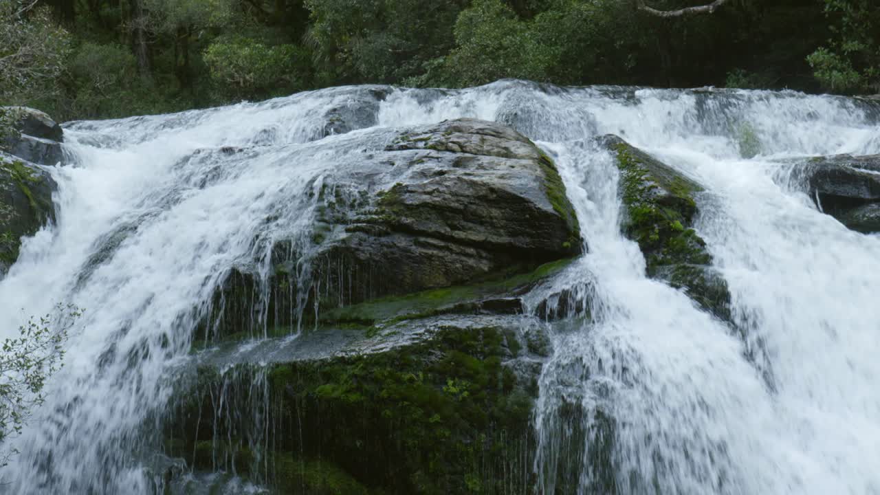 Witness the mesmerizing spectacle as water boldly splits into two streams, creating a striking and unique display in the heart of a majestic waterfall