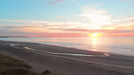 Una-Marea-Baja-Tranquila-En-La-Playa-Cerca-De-La-Barrera-De-Marejada-En-El-Suroeste-De-Los-Países-Bajos,-Durante-La-Puesta-De-Sol