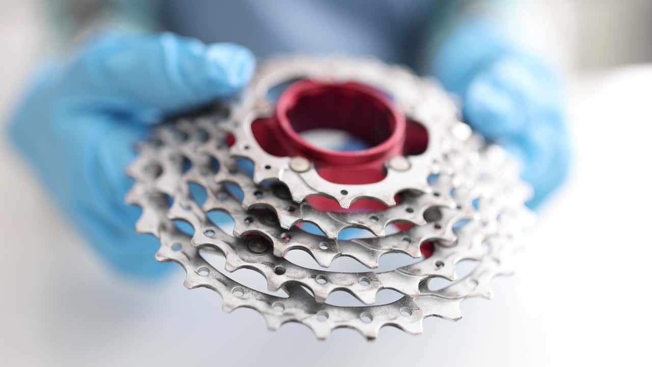 maestro de reparación sosteniendo en sus manos en guantes bicicleta cassette de metal primer plano película 4k
