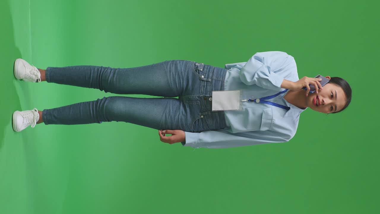 cuerpo lleno de mujer de negocios asiática hablando por teléfono móvil en la pantalla verde en el estudio