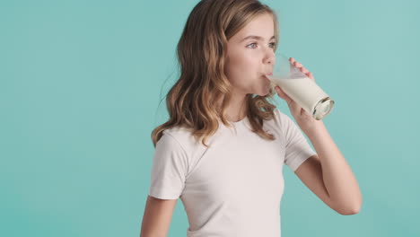 teenage caucasian girl in pijamas drinking milk from a glass and smiling.