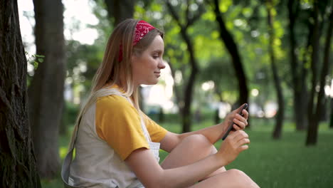 mujer muy joven usando su teléfono inteligente en un parque verde