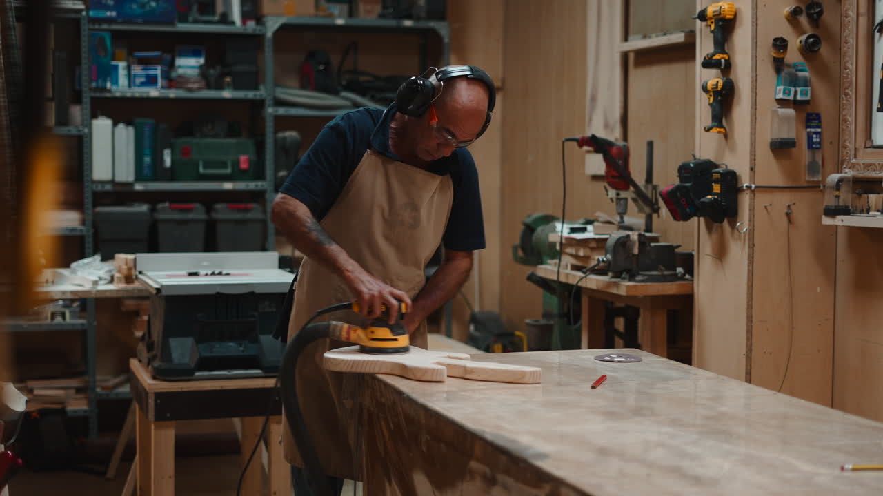 Skilled Carpenter Sanding a Wooden Guitar Body in a Workshop