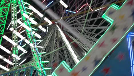 carnival with ferris wheel, bright colourful lights, car carousel at night closeup