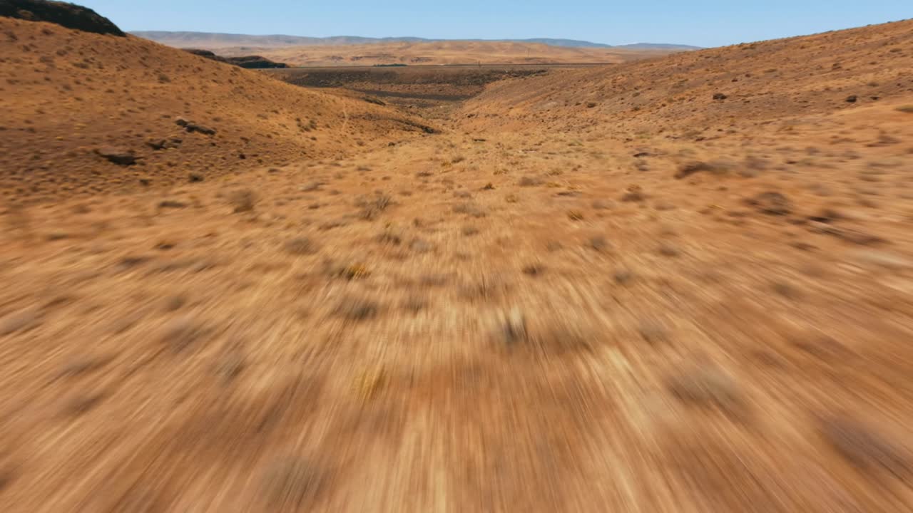 Drone da corsa FPV che vola a bassa quota ad alta velocità vicino al suolo in una zona remota della costa occidentale degli USA.