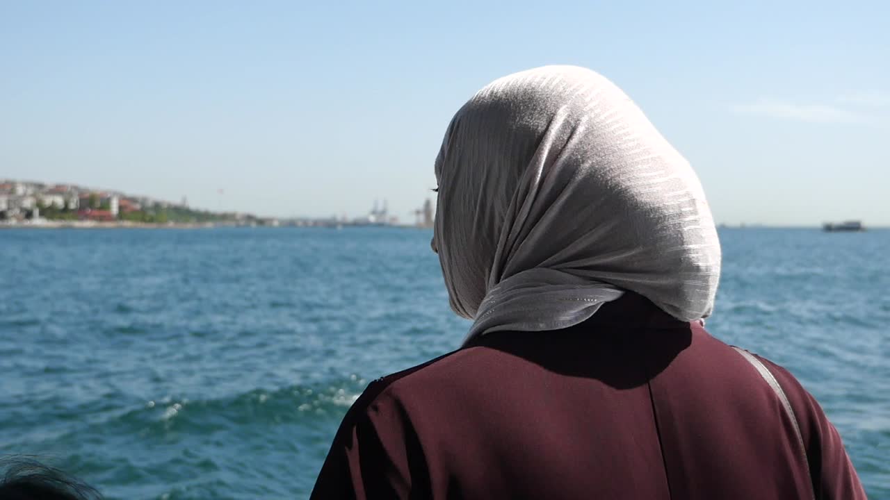 히자브 를 입은 여자 가 바다 를 바라보고 있다
