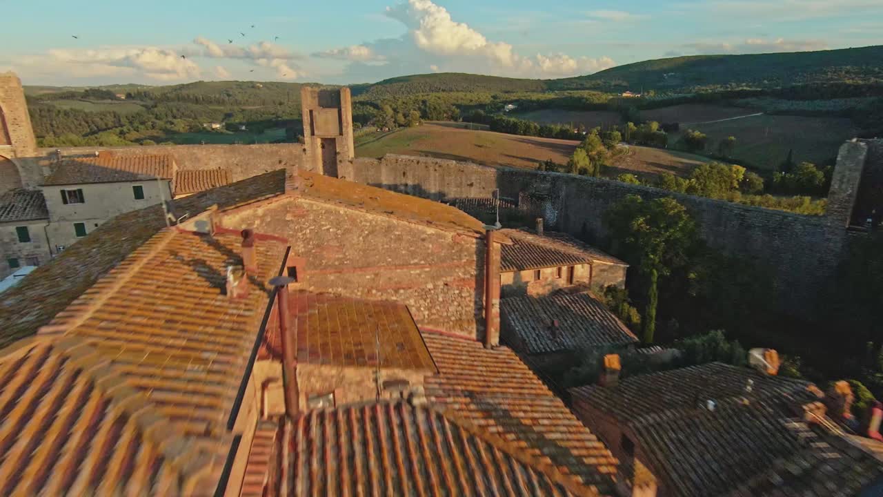 vuelo rápido sobre la comuna de monteriggioni al atardecer, provincia de siena, italia