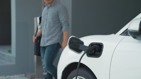 un hombre progresista desconecta el cargador del vehículo eléctrico en su residencia.