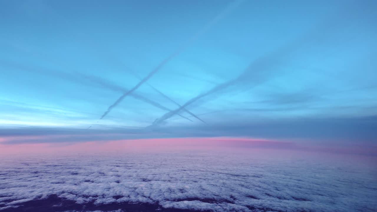Vista aerea di molteplici scie di condensazione di jet catturate all'alba dalla cabina di pilotaggio, mentre si vola tra strati di nuvole eteree e un orizzonte violaceo.