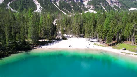 small beach with people under croda del becco mountain in lago di braies