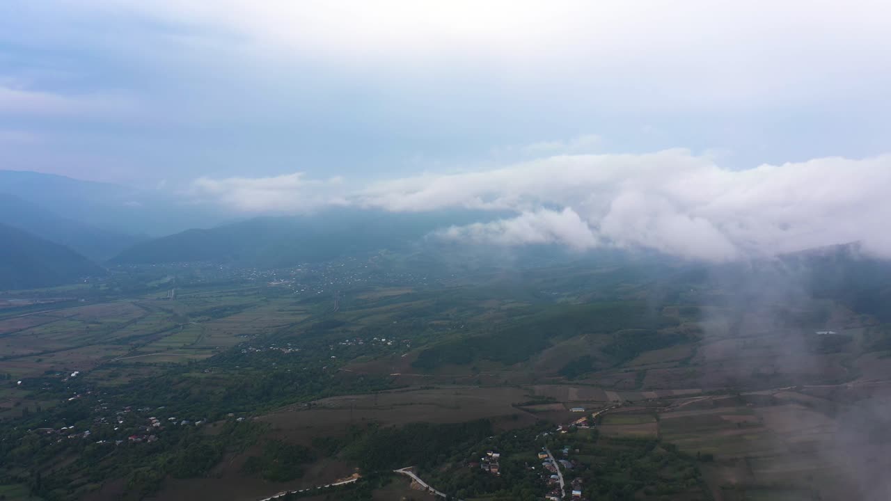 조지아의 사이르미 근처 마을, 들판, 산 위에 흰 구름과 안개