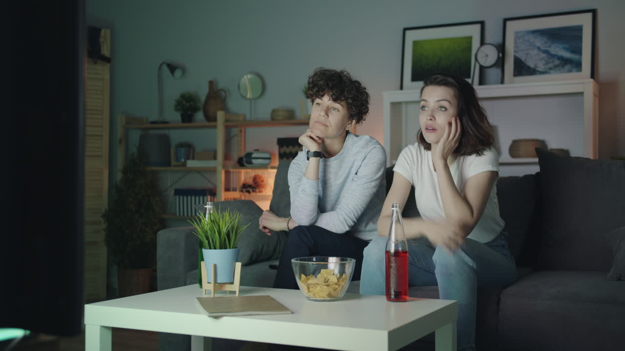 Two women watching TV at home
