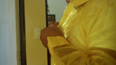 elder filipino man buttoning yellow barong in his room