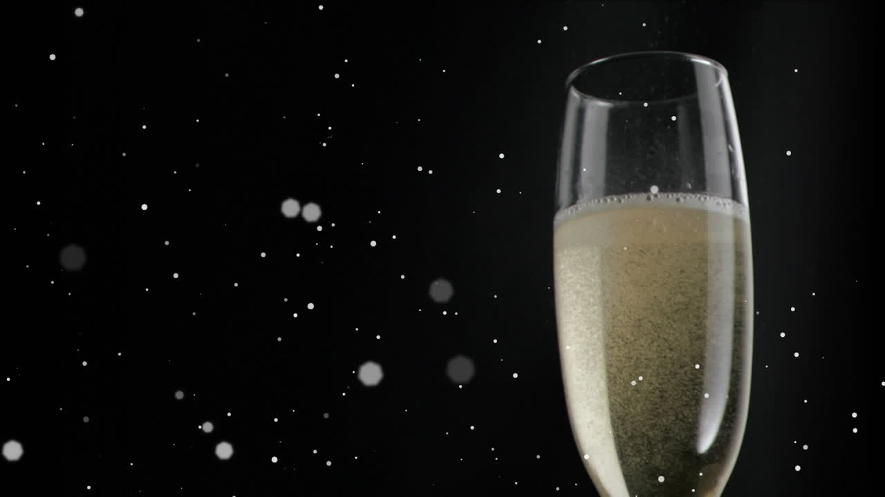 Animazione di particelle bianche che fluttuano su bicchiere di champagne su sfondo nero.
