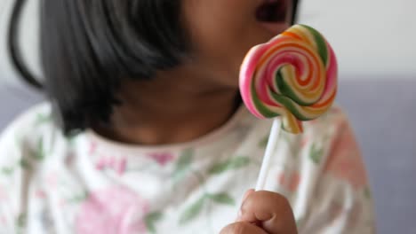 child is licking ful candy on stick