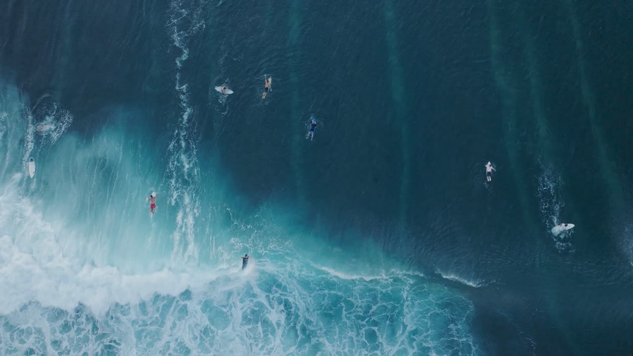 top down drone de surfistas y acción de olas en marea baja sobre coral y arrecife de roca al atardecer, playa de bingin, bali, uluwatu indonesia
