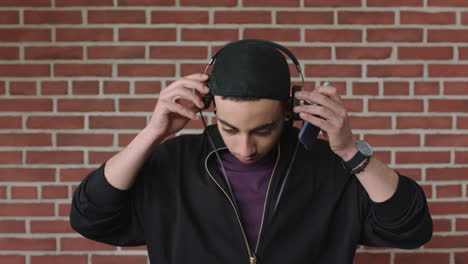 attractive young hispanic man portrait of student listening to music on headphones using phone