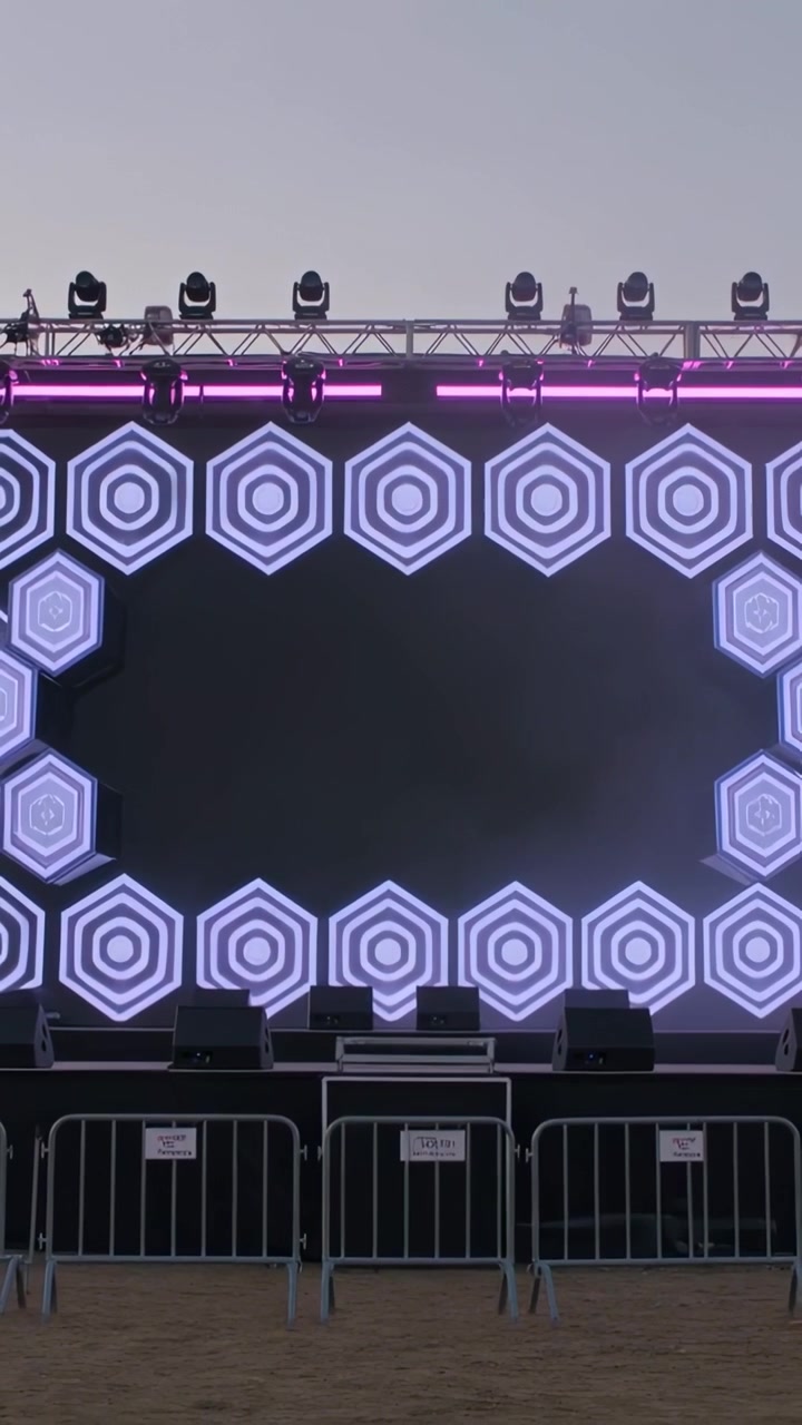 Vertical video: Pulsing LED screen and truss during preshow at outdoor stage showing hexagon border