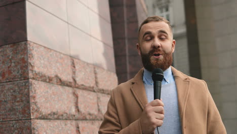 smiling caucasian male journalist speaking on the microphone in the street in autumn