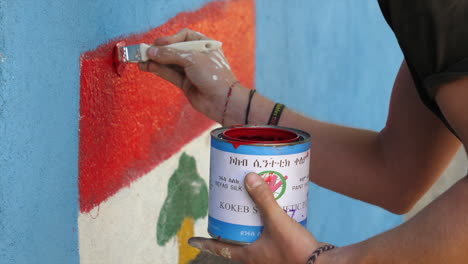 oromia region flag is being painted by charity event staff member on school wall