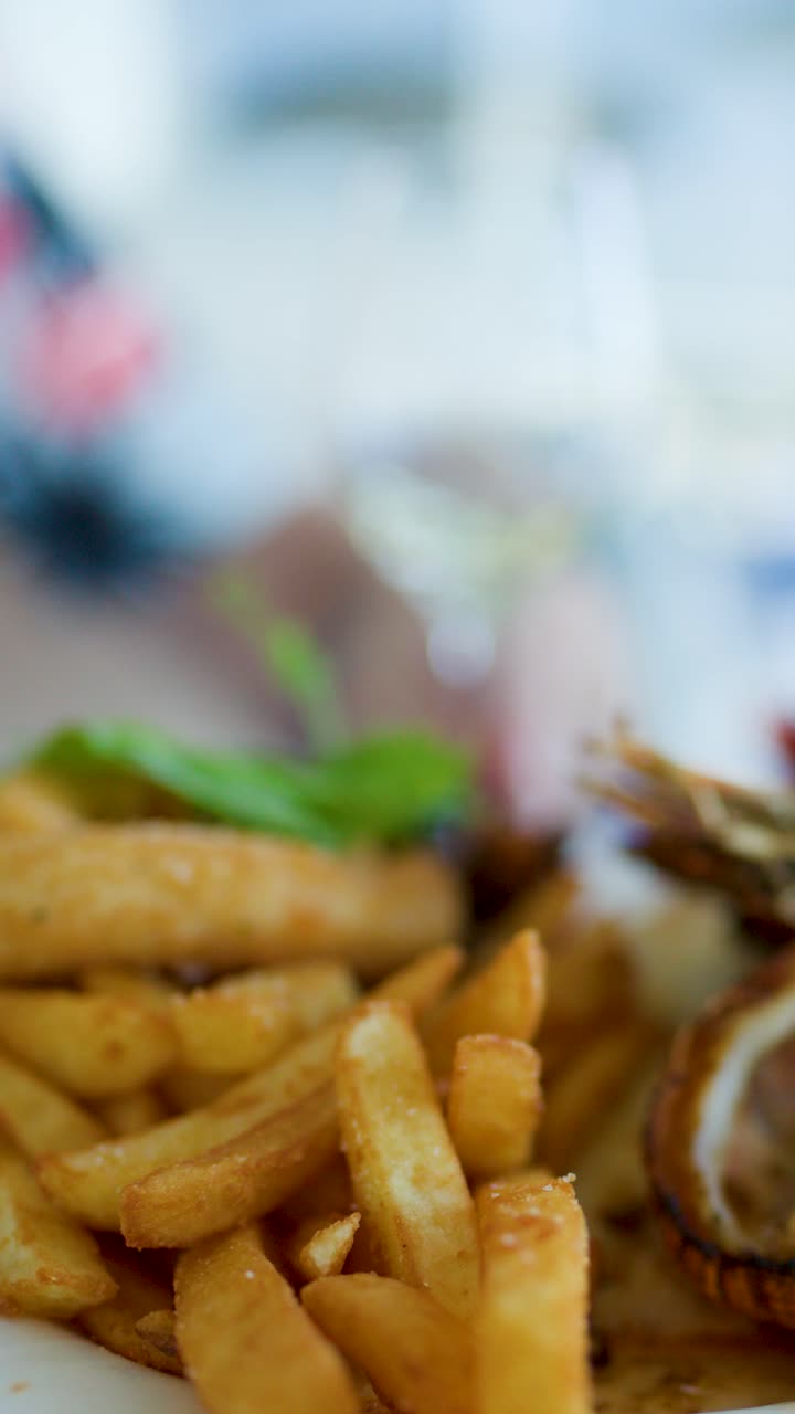 Golden fries and battered fish on plate, restaurant setting, shallow focus, smooth camera pan