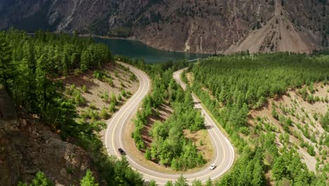 beautiful winding u-shaped road slow - sunny moving traffic mountain forest view 4k