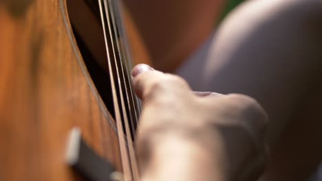 girl playing her guitar under the sunlight -close up