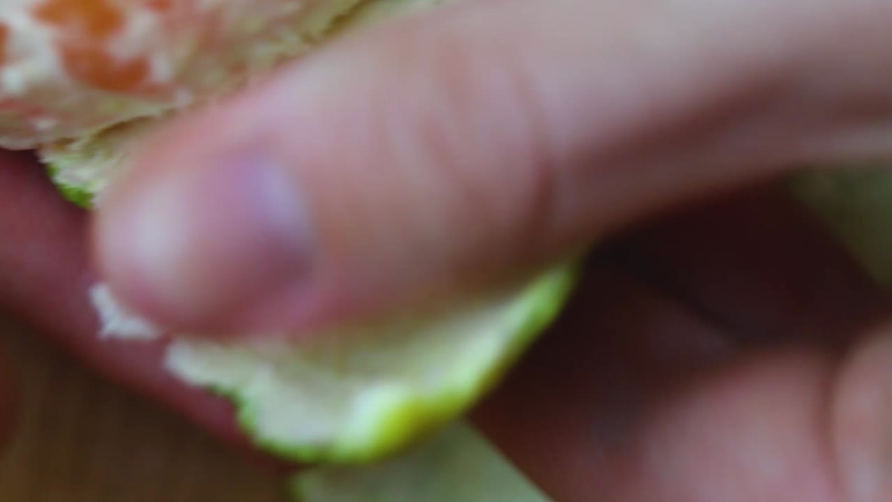 manos pelando fruta mandarina verde - macro