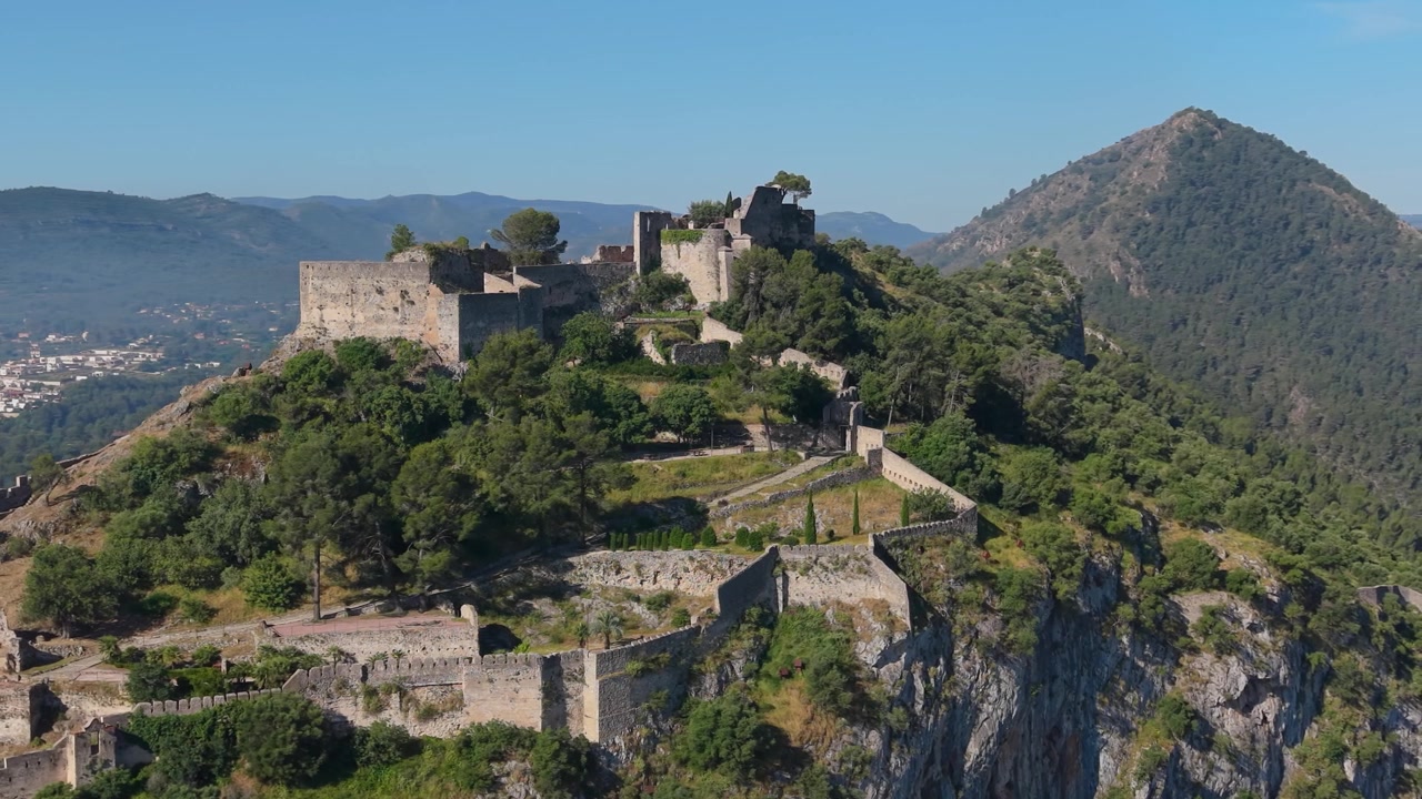 Vista aerea con drone della fortezza superiore del Castello di Xàtiva arroccata su una cima di montagna sopra scogliere aspre e valli boscose a Xàtiva, Spagna.